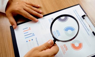 Businessman looking at marketing research documet with a magnifying glass