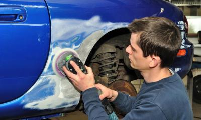 Employee preparing a car for a paint job in a car bodyshop