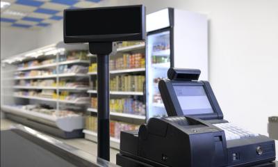 Black cash register with refrigerated products in background