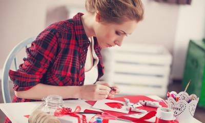 Woman in red shirt sat down at table making rural crafts