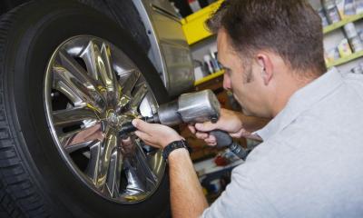 Tyre fitter attaching a wheel to a car in his garage